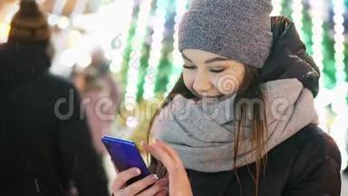 年轻女子在<strong>雪夜</strong>、圣诞节和新年使用手机应用程序